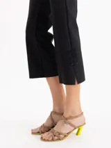 Pantalón negro de tiro alto y calce ajustado, con recortes centrales y tajos en los laterales del ruedo decorados con pequeños moños satinados.