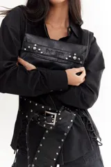 Sobre de cuero negro con solapa, cierre magnético y muñequera con tachas plateadas.