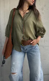 Camisa verde de tejido liviano, con cuello romántico con volados, mangas abullonadas tres cuartos con puños fruncidos y cierre frontal con botones.