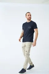 Pantalón cargo de corte slim, color negro, con bolsillos laterales con solapa y botones metálicos. Cuenta con cierre frontal, botón en la cintura y pasacintos.