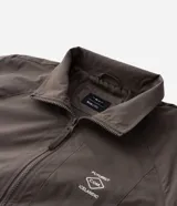 Campera rompeviento color verde militar, con cierre frontal de cremallera, cuello alto, puños y cintura elásticos. Presenta recortes delanteros y un pequeño logo estampado en el pecho.