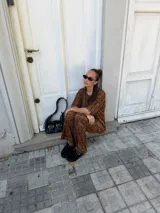 Conjunto de dos piezas compuesto por una remera de manga corta y un pantalón de corte acampanado, ambos confeccionados en lanilla con estampado animal print en tonos marrones.