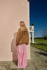 Falda larga color rosa pálido, de corte recto y confeccionada en gasa con volados verticales.