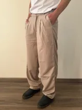 Pantalón sastrero de corte recto y holgado, color gris claro, con pinzas frontales y cintura con elástico posterior.