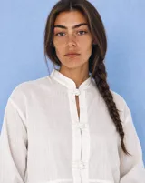 Camisa de lino color blanco, de manga larga, con cuello mao y cierre frontal con nudos de pasamanería.
