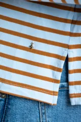 Remera de manga larga con cuello redondo, confeccionada en algodón con elastano. Presenta un diseño de rayas horizontales en color azul marino sobre fondo blanco.