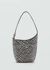 Bolso tipo bucket con estampado de cebra en tonos grises y negros. Tiene asa corta, cierre de botón magnético, detalle metálico dorado y forro interior.