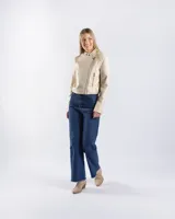 Campera estilo motero de símil cuero en color beige, con cuello alto, cierre frontal asimétrico y paneles acolchados en los hombros.