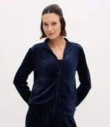 Campera deportiva de mujer confeccionada en tejido plush aterciopelado. Presenta cuello alto, cierre frontal con cremallera y puños ajustados.