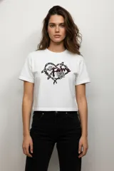 Remera de algodón color beige con cuello redondo y mangas cortas. Presenta un estampado frontal de dos cerezas con diseño de animal print de leopardo.