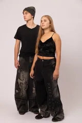 Pantalón de jean negro con proceso de lavado localizado, corte balloon fit de volumen curvo, detalles de bordados tipo costura expuesta y parches desflecados.