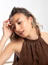 Aros tipo ear cuff dorados con diseño en abanico compuesto por piezas metálicas alargadas y tridimensionales similares a pétalos.