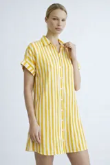 Vestido camisero de silueta relajada, con cuello clásico, cierre frontal de botones y mangas cortas con dobladillo. Presenta un estampado de cuadrícula irregular en color rojo sobre fondo blanco.