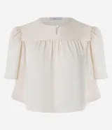 Blusa cropped de satén color crema, con cuello redondo, mangas cortas abullonadas con hombreras y detalle de fruncido en el frente.