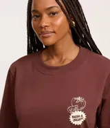 Remera marrón de algodón y poliéster, con cuello redondo y mangas cortas. Estampa en la espalda con la palabra "Market" y dibujo de vegetales.