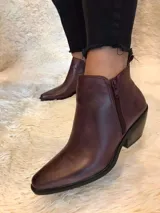Botín de cuero color borgoña, con punta fina, cierre lateral y taco bajo de madera.