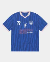Camiseta de fútbol de manga corta en color azul con diseño estampado abstracto y cuello en V rosado con detalles blancos a juego con los puños. Presenta inscripciones y escudos deportivos en el pecho.
