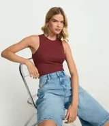 Body básico color bordó, de ribana de poliamida con superficie acanalada. Prenda sin mangas, con cuello halter y cierre en la entrepierna.