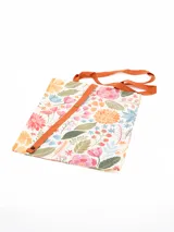 Tote bag plegable con estampado floral multicolor sobre base blanca, tiras de hombro y cinta de cierre en color tostado.