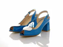 Sandalias de charol azul con taco ancho mediano, diseño peep toe y tira ajustable al talón con hebilla dorada. Incluyen un aplique removible en forma de corazón blanco en la parte delantera.