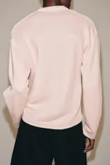 Sudadera de algodón en color rosado, con escote en V y mangas largas de corte holgado.