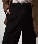 Pantalón de sastrería corte wide leg, color negro, con pliegues delanteros, bolsillos traseros embutidos y cinturón fino incluido.