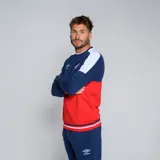 Buzo de cuello redondo Umbro del Club Nacional de Football. Diseño tricolor con cuerpo superior blanco, franja central azul y detalles en rojo en hombros y puños. Incluye logo de Umbro y escudo del club en el pecho.