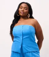 Blusa strapless de viscolino, con diseño de escote recto y recortes frontales que le otorgan una estructura entallada. Presenta un ruedo ligeramente abierto y cierre lateral mediante cremallera.