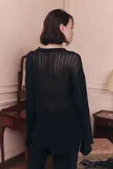 Sweater de punto calado color negro, con escote redondo y mangas largas. Presenta un diseño de tejido abierto y holgado.