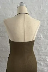 Vestido corto de microtul color verde oliva, con escote drapeado, espalda descubierta y breteles finos. Presenta un diseño ajustado con frunces laterales en toda la prenda.