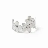 Brazalete rígido de metal plateado con diseño de flores unidas entre sí.