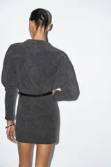 Vestido corto de tejido suave color gris oscuro, con cuello redondo y manga larga. Incluye un cinturón fino de efecto piel con hebilla metálica dorada.