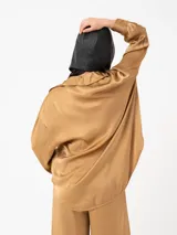 Camisa color ladrillo de corte amplio y mangas largas, con cuello camisero y cierre frontal con botones.