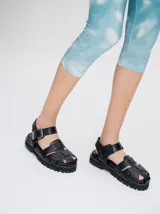 Sandalias romanas de cuero tostado, estilo chunky con plataforma y suela tractora de goma negra. Cuentan con tiras cruzadas en el empeine y tira ajustable con hebilla metálica en el tobillo.