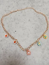 Collar dorado con cadena de eslabones gruesos y dijes de flores de colores hechas con cuentas.