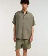 Bermuda masculina de poliéster, color negro, con lazo en la cintura, bolsillos y detalle de etiqueta gomosa.