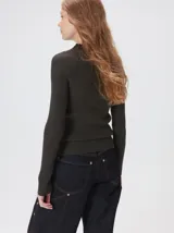 Remera de cuello alto tipo polera, confeccionada en tela rib con textura acanalada y ajuste al cuerpo. Presenta mangas largas y un pequeño bordado distintivo en la parte inferior.