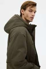 Campera parka acolchada repelente al agua y rompevientos, con cuello alto, capucha ajustable, cierre frontal con solapa y bolsillos frontales tipo parche y calientamanos.