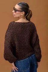 Sweater de tejido de punto grueso con textura trenzada y destellos de lurex, en color chocolate. Presenta un diseño oversize con cuello redondo amplio y mangas largas con puños ajustados.