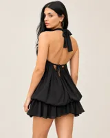 Vestido corto color chocolate con cuello halter, hombros descubiertos, silueta blusón y falda mini con volados, incluye short interno.