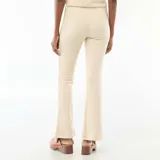 Pantalón de punto color beige, de corte flare con cintura alta y diseño ajustado en la parte superior que se ensancha hacia el ruedo.
