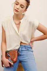 Camisa sin mangas color marfil, con cuello mao y cierre frontal de botones, corte amplio y diseño fluido.