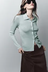 Chaqueta estilo polo de manga larga confeccionada en tejido de punto con hilo metalizado. Presenta cuello solapa y cierre frontal con botones.
