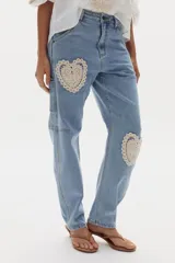 Pantalón estilo cargo confeccionado en denim celeste, de corte recto y holgado. Presenta apliques decorativos circulares de crochet en tonos beige en los laterales y bolsillos utilitarios.