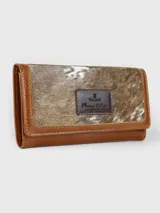 Billetera combinada de cuero en tonos marrón y camel, con solapa frontal de pelo vacuno estampado y detalle de placa con el logo de la marca.