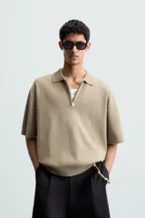 Polo de punto color verde oliva, de manga corta y corte relajado. Presenta cuello solapa con cierre frontal de cremallera.