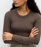 Blusa de manga larga con cuello redondo, confeccionada en tejido rib acanalado. Presenta un diseño ajustado al cuerpo y textura vertical en relieve.