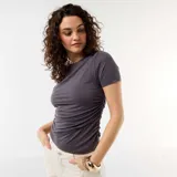 Remera gris de manga corta y cuello redondo, con diseño ajustado al cuerpo y fruncidos en el lateral izquierdo.