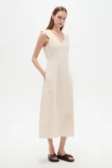 Vestido midi de viscosa color natural, sin mangas, con cuello en V, pinzas de ajuste y bolsillos laterales.