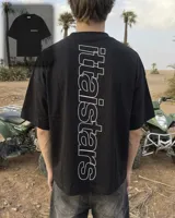 Remera negra oversize de manga corta, con estampa tipográfica vertical en la espalda y logo pequeño en el frente.